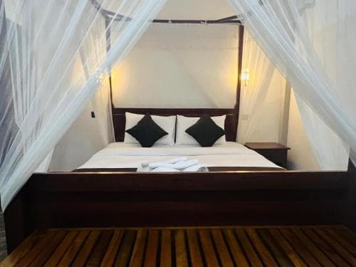 Hidden Cove canopy bed seen from the wooden bench at the foot