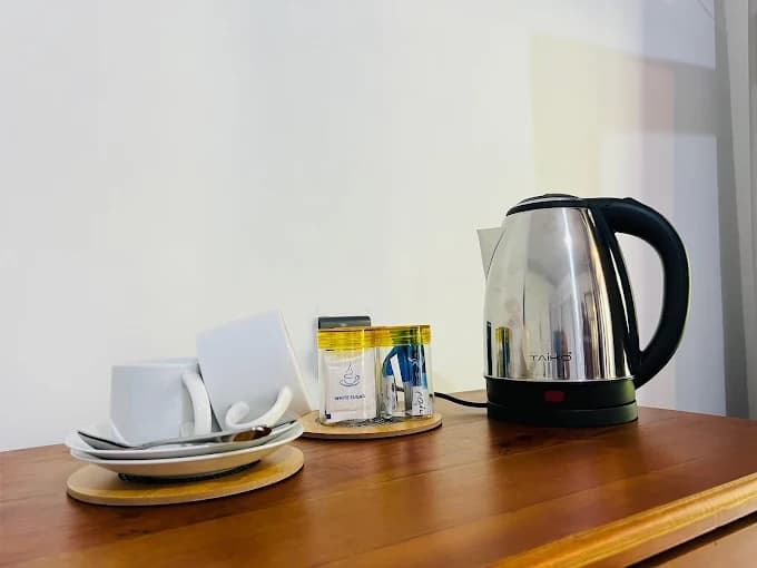Tea tray with kettle, cups and sugar on a wooden cabinet